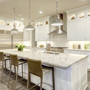White kitchen design features large bar style kitchen island with granite countertop | Pierce Flooring