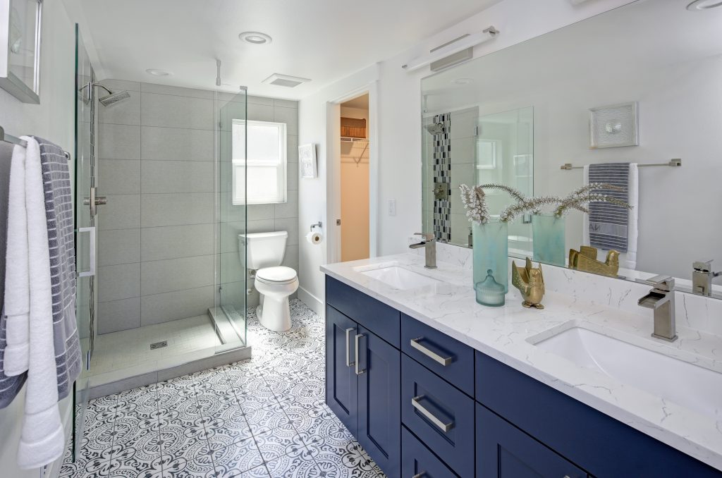 Modern bathroom interior with blue double vanity and glass shower | Pierce Flooring