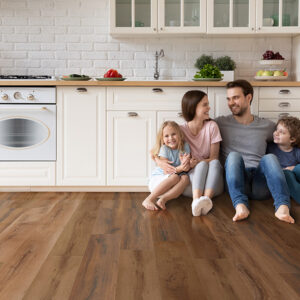 Happy young family with little children sit on warm wooden floor | Pierce Flooring